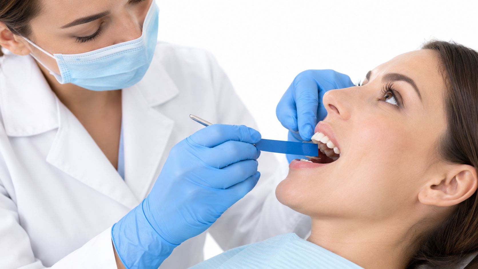 A female dentist checking a patient's bite with an articulating paper strip during a dental consultation.